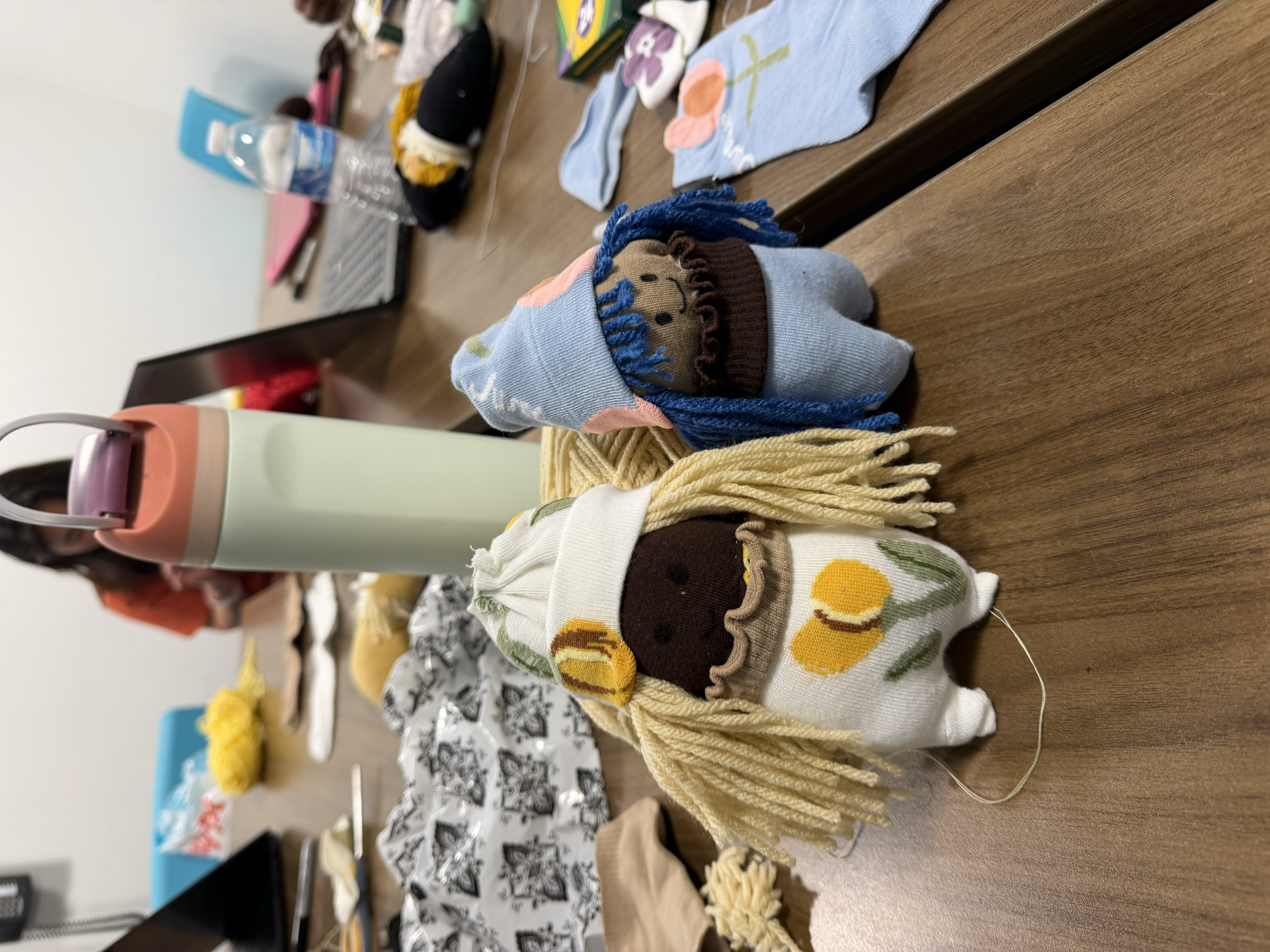 Handmade dolls and craft supplies on a table at Make a Difference Day